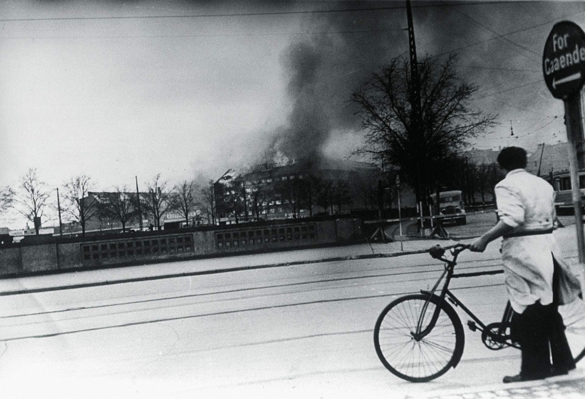 Cyclist_looking_at_the_burning_Shellhouse_(Getapos_head_quarter)_after